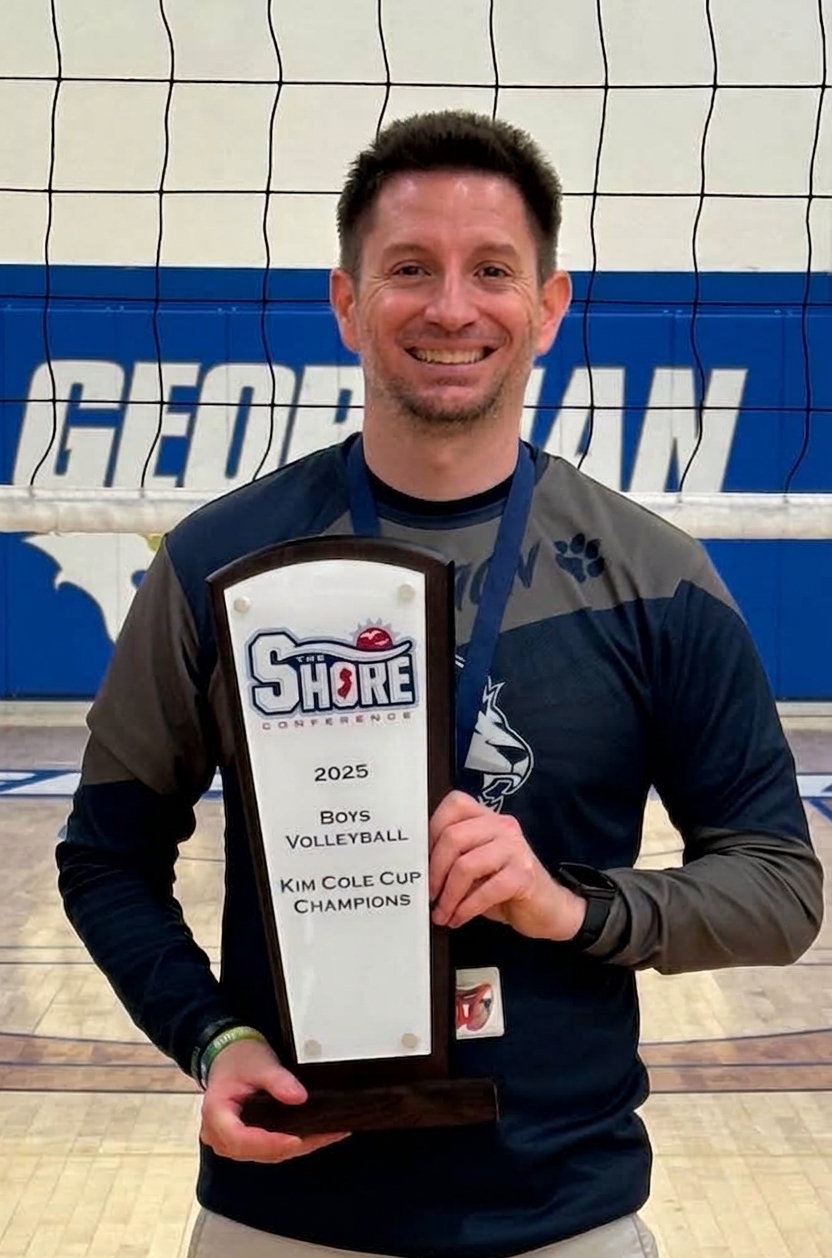 The founder of CourtPage™ Volleyball holding a Shore Conference championship trophy on the court.